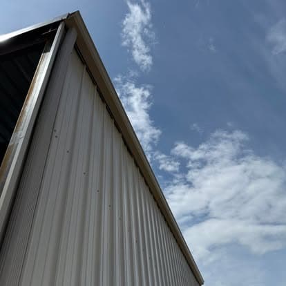 Metal building structure against a blue sky with scattered clouds.