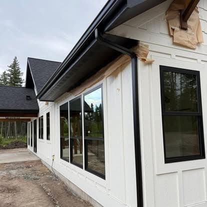Newly constructed home exterior with large black-framed windows and fresh white siding.