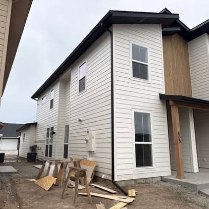 Newly constructed modern home exterior with wooden accents and construction materials nearby.