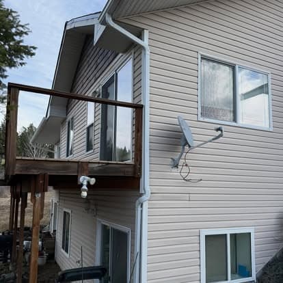 Modern house exterior featuring a balcony, windows, and satellite dish under blue sky.