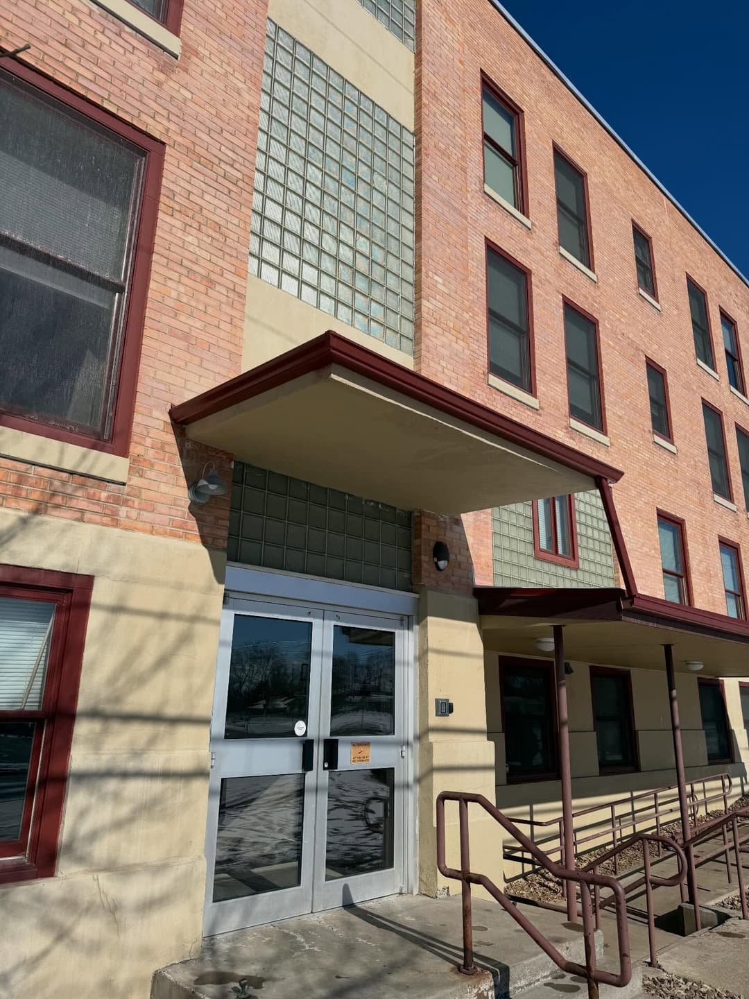 Brick building entrance with glass block windows and accessible ramp on a sunny day.