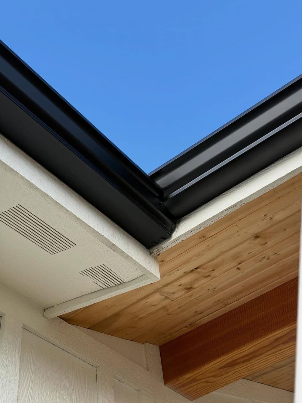 Modern roof design featuring wooden beams and clear blue sky. Stylish architectural details.